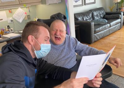 Jim reads a birthday card, smiling, with a staff member