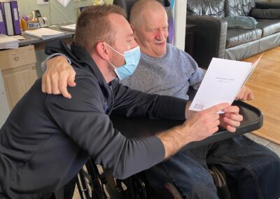 Jim reads a birthday card, smiling, with his staff member